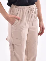 Pantalón beige tipo jogger con elásticos en los tobillos y bolsillos laterales.