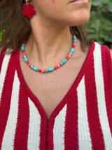Collar corto con cuentas de colores turquesa, rosa, naranja y blanco con negro. Se cierra con cadena de acero quirúrgico y ganchito para regular el largo.
