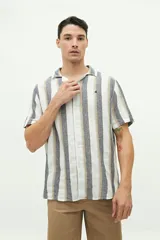 Camisa de manga corta confeccionada en lino y algodón a rayas verticales en tonos blanco, gris y beige. Tiene cuello tipo cubano, corte regular y logo bordado en el pecho.