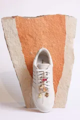 Zapatillas bajas de gamuza celeste con cordones y pañuelos estampados atados a los cordones.