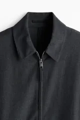 Campera gris oscuro de sarga con cuello clásico, cierre frontal con cremallera, bolsillos laterales insertados al bies, puños con botón a presión y forro interior.