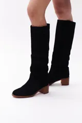 Bota de caña media de cuero color negro, con taco de madera y punta redondeada.