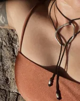 Collar con dije circular irregular de alpaca y plata 925, con hilo de algodón natural.