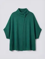 Capa o poncho tejido color verde esmeralda, con cuello polera alto que se cierra con un botón grande en el lateral. Presenta mangas cortas estilo japonesa y un calce amplio.