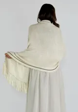 Chaleco tipo pashmina tejido en color blanco con detalles plateados y flecos en el borde inferior.
