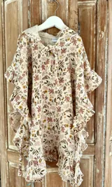 Salida de baño para niñas en tela muselina estampada con girasoles, con capucha y lazo a los costados. Cuello a la base con abertura y lazo para cerrar el escote. Volado romántico alrededor.