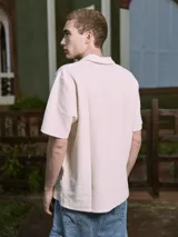 Polo de manga corta color crema, con cuello tipo polo y corte relajado.