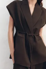 Chaleco color crudo confeccionado en hilatura con lino y viscosa. Tiene cuello solapa de muescas y manga sisa caída. Cierre frontal cruzado con cordones.