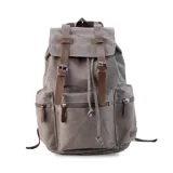 Mochila de tela canvas color verde oliva con tapa y detalles en símil cuero marrón. Cierre superior marinero, bolsillos internos, externos frontal, laterales y trasero con cierre. Asas rígidas, correas ajustables y espacio para laptop de 15".