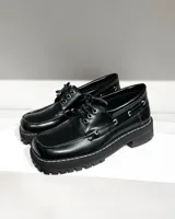 Mocasines negros de cuero vacuno con cordones, ojalillos metálicos y suela track.