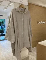 Camisa celeste de lino con corte amplio, cuello clásico, cierre frontal con botones de nácar y bolsillos laterales invisibles.