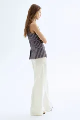 Pantalón blanco de lino con cintura elástica, bolsillos al bies y bolsillos traseros insertados. Piernas rectas con pliegue cosido adelante.
