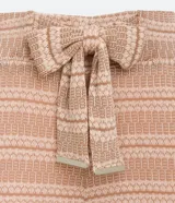 Pantalón largo de tejido de punto con rayas horizontales en tonos beige y marrón claro. El pantalón es de corte flare, con cintura alta y lazo para ajustar.