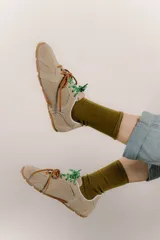 Zapatillas urbanas de cuero color tostado, con cordones verdes y suela de goma.