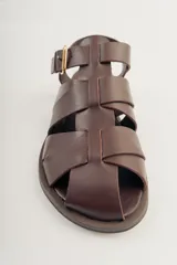 Sandalias bajas de cuero marrón con tiras entrecruzadas y hebilla dorada.
