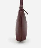 Bandolera pequeña color borgoña, de cuero sintético, con correa fina regulable y cierre superior con cremallera.