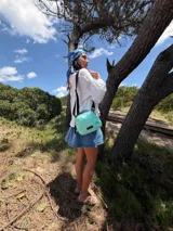 Bandolera pequeña de tela negra, con correa ancha ajustable y cierre superior.