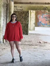 Buzo de tejido de punto color rojo, con cuello redondo y ribete celeste. Presenta costuras blancas visibles en hombros y mangas.