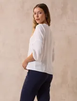 Blusa de gasa color blanco con estampado de hojas verdes, de mangas 3/4 abullonadas con puños elásticos.