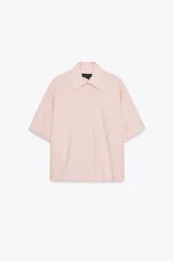 Camisa color rosa claro a rayas verticales finas color marrón, de popelín, con cuello solapa y manga corta con dobladillo. Tiene un bolsillo de parche en el pecho, aberturas laterales en el bajo y pinzas en la espalda. El cierre frontal es con botones ocultos.