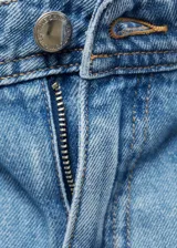 Pantalón largo de denim, color celeste claro, de tiro alto y pierna ancha. Presenta dos bolsillos de parche delanteros y dos bolsillos traseros.