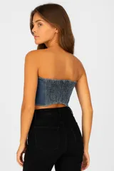 Top strapless de jean azul con tres tiras horizontales con hebillas plateadas.