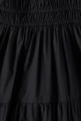 Vestido corto negro sin mangas en tejido fresco de algodón. Modelo con escote cruzado en V, pliegues en los hombros, cintura fruncida y pollera con vuelo.