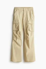 Pantalón cargo color beige de lona de algodón, de tiro bajo con elástico en la parte posterior de la pretina y cierre con botón a presión. Piernas amplias con bolsillos al bies y bolsillos de fuelle con solapa.