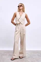 Pantalón de lino color beige, de corte palazzo con pinzas y bolsillos laterales. Se combina con chaleco de lino a juego.