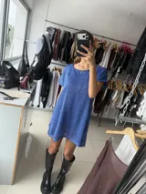 Vestido corto azul con brillo sutil, de tejido liviano y caída fluida. Cuenta con forro interno, mangas cortas y tajos laterales.