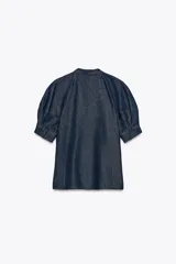 Camisa de denim azul oscuro con cuello redondo ajustable con lazadas, mangas cortas abullonadas, efecto lavado, bajo recto y cierre frontal con botones.