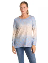 Remera de manga larga con escote redondo, confeccionada en tejido soft. Presenta un estampado tipo damasco o arabesco con efecto degradado, pasando de azul claro en la parte superior a beige/dorado en la parte inferior.