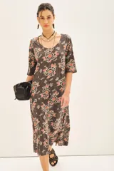 Vestido midi con estampado floral en tonos marrones, naranjas y blancos. Tiene mangas 3/4, escote en V y corte en línea A.