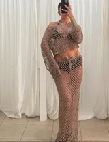 Conjunto de dos piezas de tejido de red (crochet) color blanco, compuesto por un top manga larga cropped y una falda larga ajustada con cordón de ajuste.