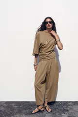 Pantalón color marrón claro, de tiro medio, corte ancho y largo tobillero. Cuenta con cintura elástica ajustable con cordones y bolsillos laterales ocultos en la costura.