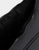 Cartera saca negra de tela deportiva con correa regulable, cierre superior y bolsillo frontal con cierre. Incluye charm lateral.
