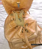 Mochila de cuero color camel con solapa con flecos y cierre con cordón de cuero.