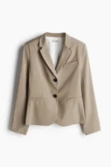 Blazer color beige de corte entallado, con solapas de muesca, bolsillo superior insertado y bolsillos delanteros. Modelo con hombreras, botonadura frontal, botón decorativo en los puños y abertura atrás.