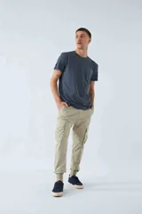 Pantalón cargo color beige, corte slim, con elástico en cintura y cordón ajustable, bolsillos cargo con botones y puños elásticos.