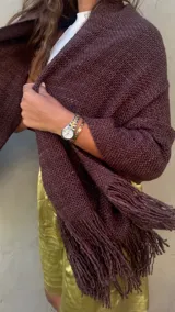 Ruana artesanal tejida en telar con lana merino de alta calidad, color marrón chocolate obtenido con teñido natural. Presenta un tejido grueso y textura visible, con flecos largos en el borde inferior.