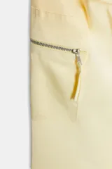 Pantalón cargo color blanco hueso, de tiro medio, corte ancho y tela satinada. Incluye cinturón con hebilla metálica, bolsillos delanteros, laterales con cierre y traseros de vivo. Cierre frontal con cremallera y ganchos metálicos.