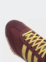 Zapatillas Adidas SL 72 OG W, color borgoña con rayas amarillas y detalles en fucsia. Inspiradas en el modelo original de 1972, con exterior de piel y revestimientos de gamuza.