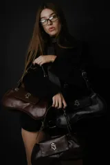 Cartera tipo baguette de cuero nobuk color musgo con detalles en cuero marrón. Tiene correa al hombro regulable, cierre YKK de aluminio plateado, chapa de marca central y logo grabado en la parte trasera.