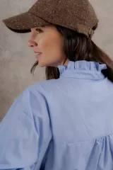 Blusa blanca de algodón con cuello mao, mangas largas y pechera con alforzas y volados. Se abrocha con mini botones de nácar.