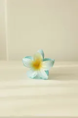 Pinza de pelo plástica con forma de flor hawaiana celeste con centro amarillo.