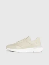 Zapatillas urbanas color beige, confeccionadas en cuero y tela, con suela blanca y cordones. Presentan monograma de la marca en el lateral.