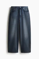 Pantalón de jean azul oscuro de corte holgado, con tiro bajo, cinco bolsillos y pierna extra ancha con pliegues en el tobillo.