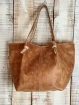Bolso tote de cuero color suela con textura irregular, doble asa de hombro con detalle de nudo decorativo y costuras a contratono.