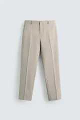 Pantalón de vestir color beige, corte slim fit, con bolsillos laterales y traseros con doble vivo y botón. Cierre frontal con cremallera y botón.