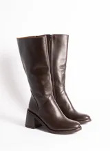 Bota de cuero vacuno color marrón chocolate, con caña alta, taco cuadrado de madera forrado en cuero y cierre interno YKK.